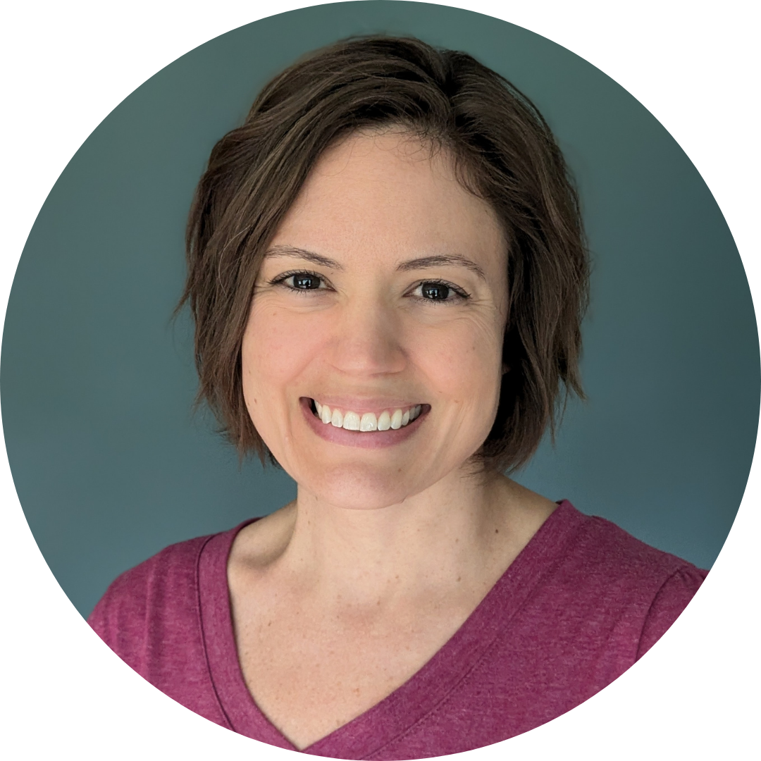 A circular headshot of a smiling woman with short, wavy brown hair, wearing a pink V-neck shirt against a solid teal background.